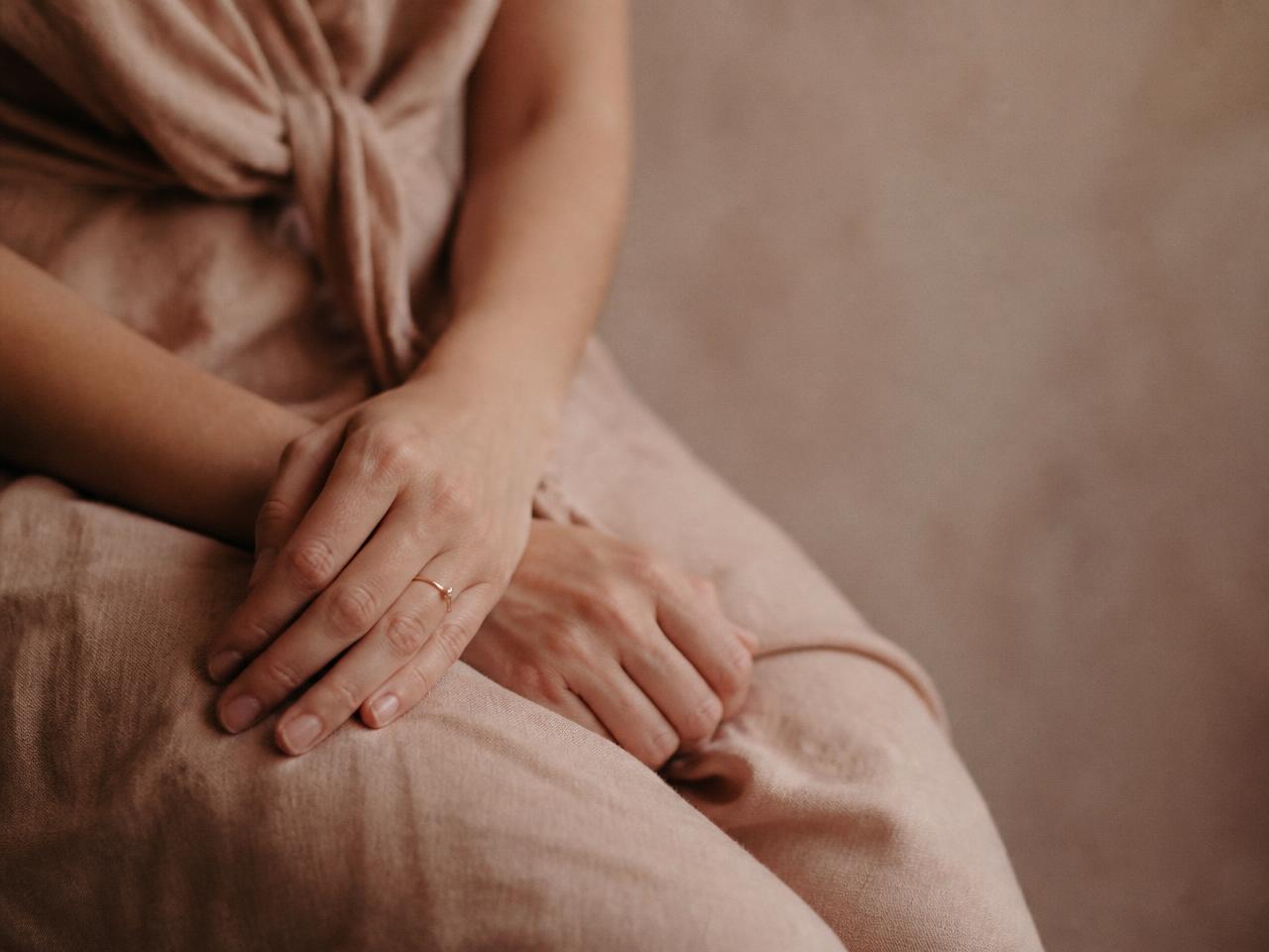 Mãos de uma mulher em repouso sobre tecido de linho, em luz natural suave